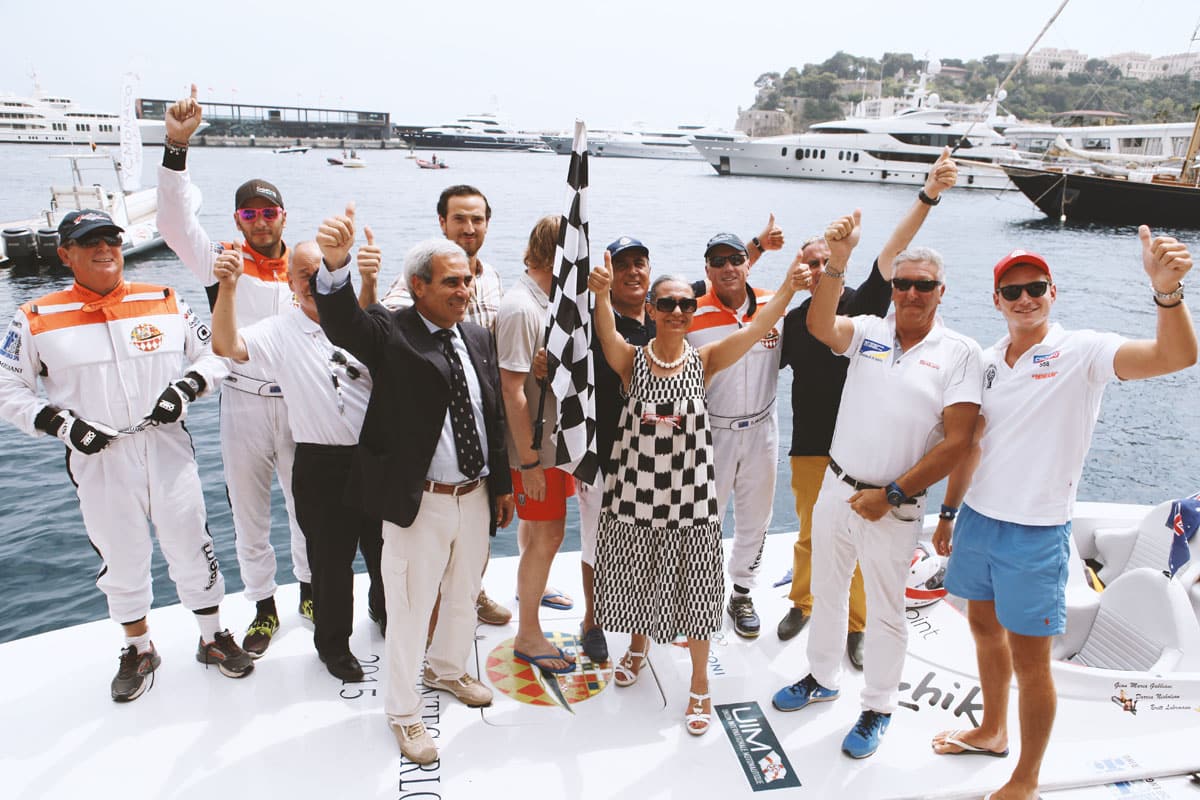Equipaggi festeggiano sul pontile con la bandiera a scacchi